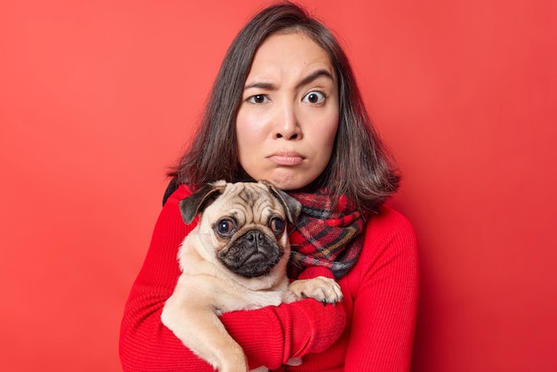 Woman holds pug with expression